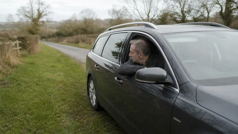 Side view of a driver pulling an estate car onto a grass verge